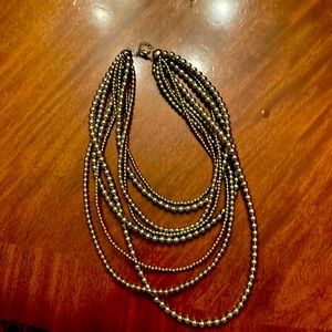 Silver toned, multi strand necklace with lobster claw clasp.